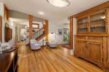 Step into a warm and inviting living space featuring beautiful natural wood floors and a charming rustic hutch.
