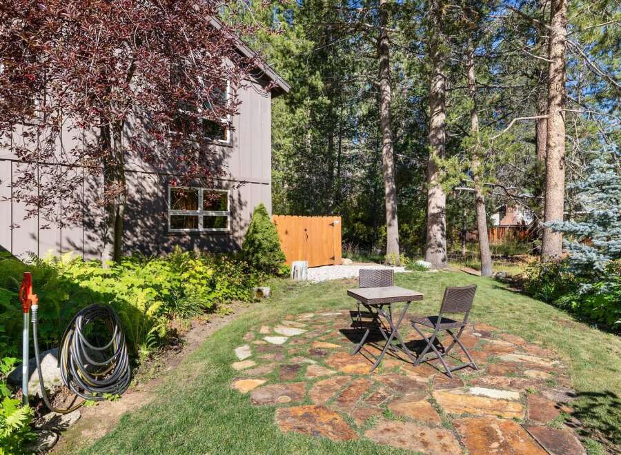 Enjoy outdoor living in this charming backyard featuring a rustic stone patio perfect for al fresco dining.