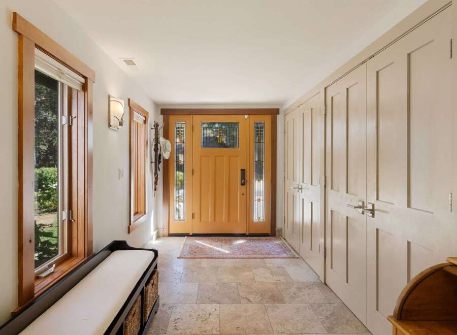 Step into this inviting entryway featuring a warm wooden front door with stained glass accents, perfect for welcoming guests.