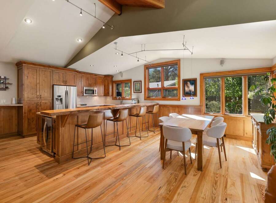 Experience the warmth of this inviting kitchen and dining area, featuring rich wooden cabinetry and a stunning live-edge breakfast bar.