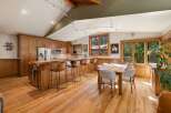Experience the warmth of this inviting kitchen and dining area, featuring rich wooden cabinetry and a stunning live-edge breakfast bar.