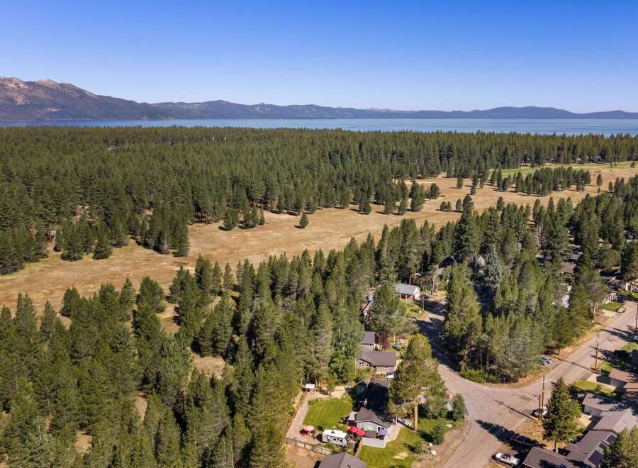 Discover this stunning property nestled amidst a lush pine forest, offering breathtaking views of a serene lake and distant mountains.