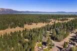 Discover this stunning property nestled amidst a lush pine forest, offering breathtaking views of a serene lake and distant mountains.