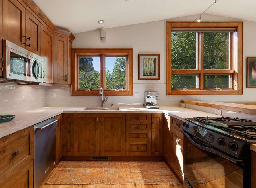 This charming kitchen features warm, custom wood cabinetry that complements the natural light streaming in from the large windows.