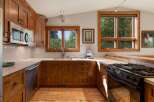 This charming kitchen features warm, custom wood cabinetry that complements the natural light streaming in from the large windows.