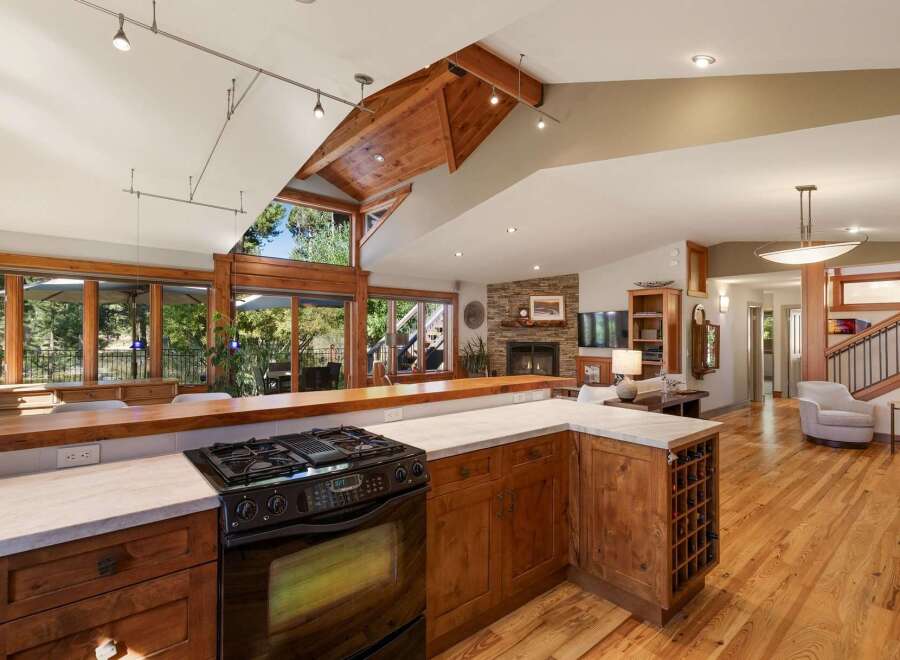 Experience the epitome of open-concept living in this stunning home, featuring a gourmet kitchen with a gas range and ample counter space, seamlessly flowing into a spacious living area with a stone fireplace.