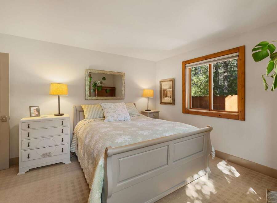 This charming bedroom features a cozy queen-size bed with a light-colored comforter and decorative pillows, perfect for a restful night's sleep.