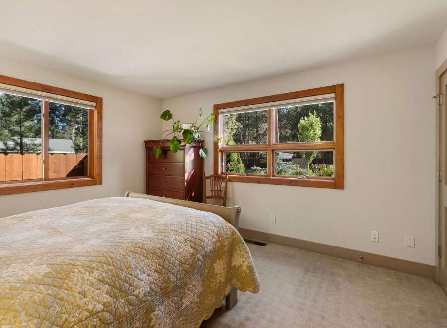 This charming bedroom features a comfortable bed with a quilted comforter, complemented by a rich wooden dresser and a decorative chair.
