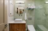 This modern bathroom features a sleek design with light green subway tile walls and a floating wood vanity.