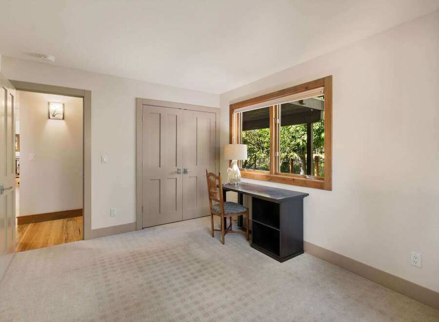 This inviting bedroom features a cozy workspace with a dark wood desk and a classic wooden chair, perfect for productivity or quiet reflection.