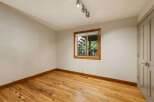 This empty room features beautiful natural light streaming in through a large window, highlighting the warm tones of the hardwood floors.