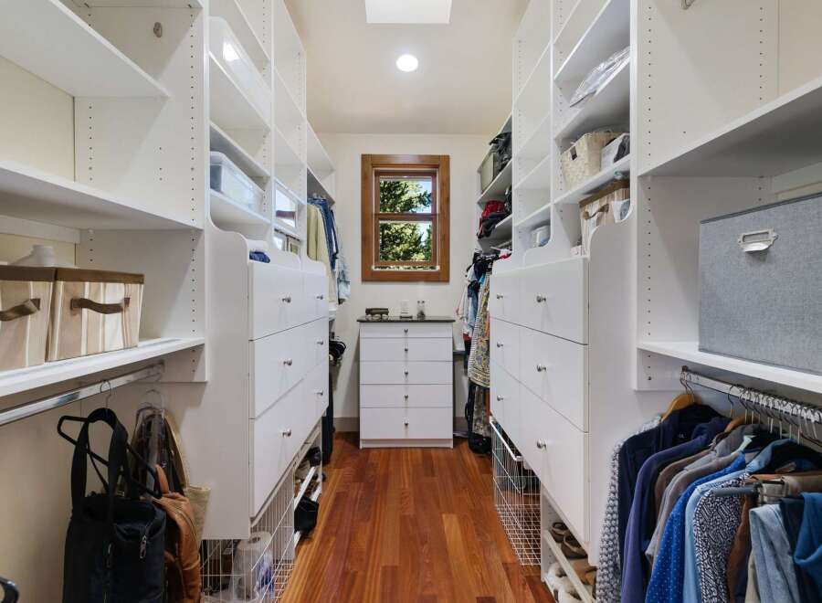 Step into this spacious walk-in closet, featuring ample white shelving and drawers for organized storage.