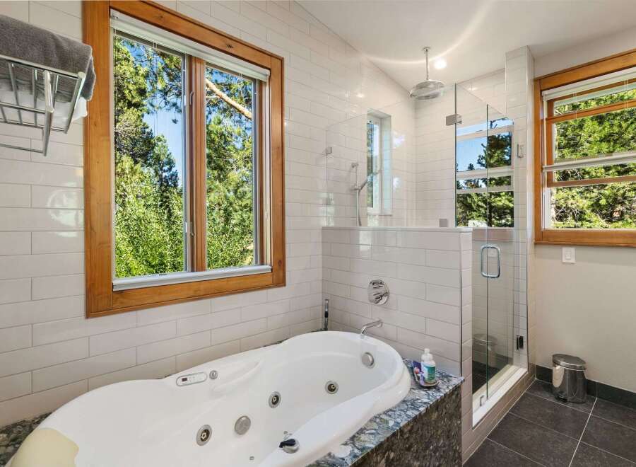 Indulge in ultimate relaxation in this luxurious bathroom, featuring a spacious jacuzzi tub with a stunning view of the surrounding greenery.