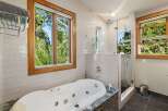 Indulge in ultimate relaxation in this luxurious bathroom, featuring a spacious jacuzzi tub with a stunning view of the surrounding greenery.