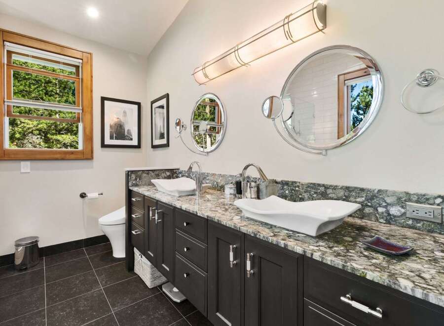 This luxurious bathroom features a spacious double vanity with elegant vessel sinks and granite countertops.