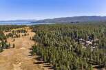 Experience the serene beauty of Lake Tahoe from this stunning aerial view, showcasing a vast expanse of lush pine forest bordering a tranquil lake.