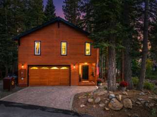Nestled amongst tall pine trees, this charming wooden home offers a warm and inviting ambiance.