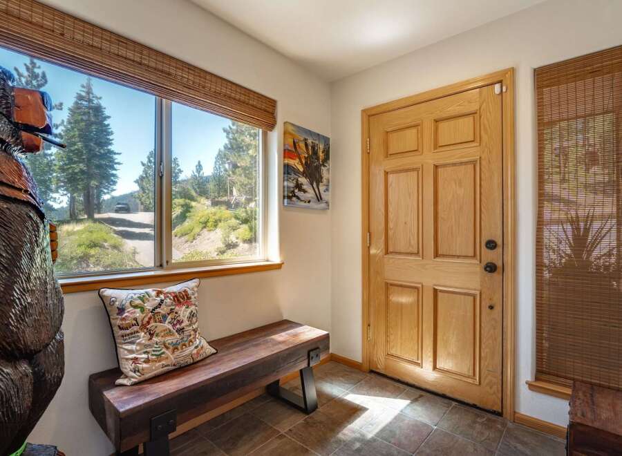 Step into this charming entryway featuring a rustic wooden bench and a large window offering scenic views of the surrounding landscape.