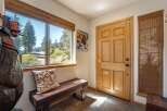 Step into this charming entryway featuring a rustic wooden bench and a large window offering scenic views of the surrounding landscape.