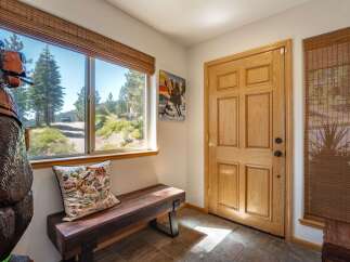 Step into this charming entryway featuring a rustic wooden bench and a large window offering scenic views of the surrounding landscape.