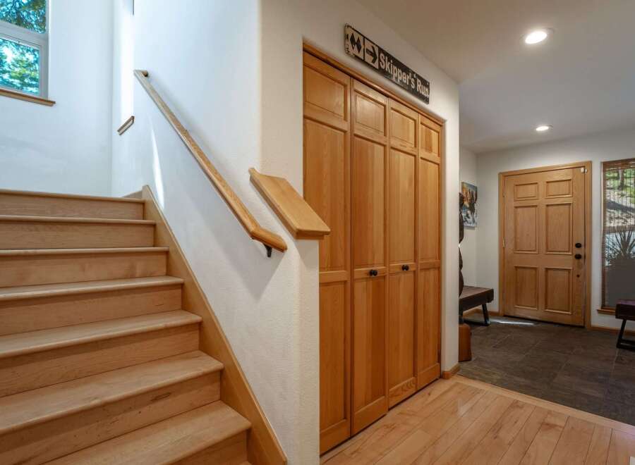 Step into this inviting entryway featuring a beautiful wooden staircase and ample storage with built-in closets.