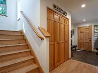 Step into this inviting entryway featuring a beautiful wooden staircase and ample storage with built-in closets.