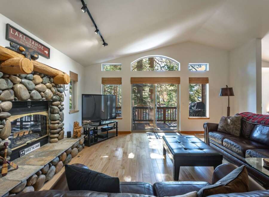 Experience the ultimate mountain retreat in this stunning living room, featuring a grand stone fireplace and a rustic log mantle.