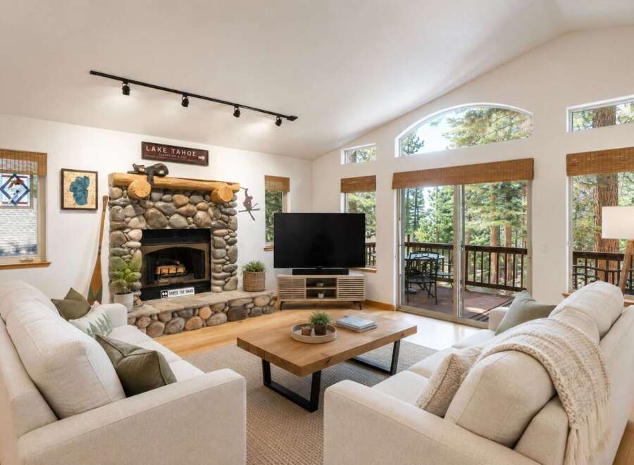 Experience the ultimate mountain retreat in this stunning living room, featuring a grand stone fireplace and vaulted ceilings with large windows that offer breathtaking forest views.