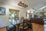 Experience cozy living in this spacious dining and living area, featuring a rustic stone fireplace and a large wooden dining table perfect for gatherings.