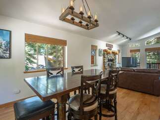 Experience cozy living in this spacious dining and living area, featuring a rustic stone fireplace and a large wooden dining table perfect for gatherings.