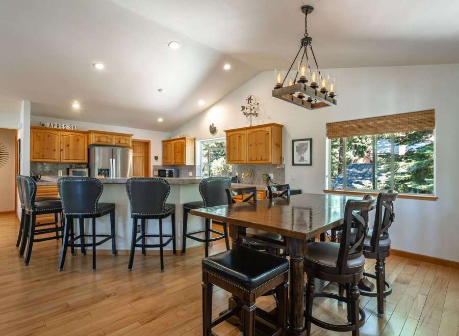 This spacious kitchen and dining area features a vaulted ceiling with recessed lighting and a rustic chandelier.