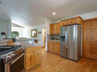 This spacious kitchen features a professional-grade stainless steel gas range and a large side-by-side refrigerator, perfect for any home chef.