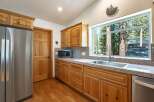 This charming kitchen boasts beautiful natural wood cabinetry and a large window offering picturesque views of surrounding trees.