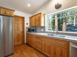 This charming kitchen boasts beautiful natural wood cabinetry and a large window offering picturesque views of surrounding trees.