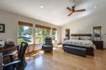 Experience serene living in this spacious bedroom, featuring large windows that flood the room with natural light and offer picturesque views of the surrounding landscape.