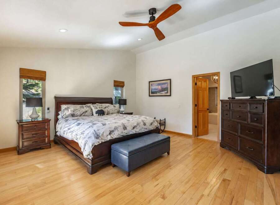 Experience ultimate comfort in this spacious master bedroom, featuring a luxurious king-size bed with charming bear-themed pillows and a plush ottoman at the foot of the bed.
