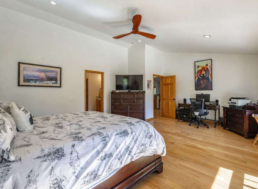 This spacious bedroom features a comfortable king-size bed with a nature-inspired duvet and a large dresser with an integrated TV.