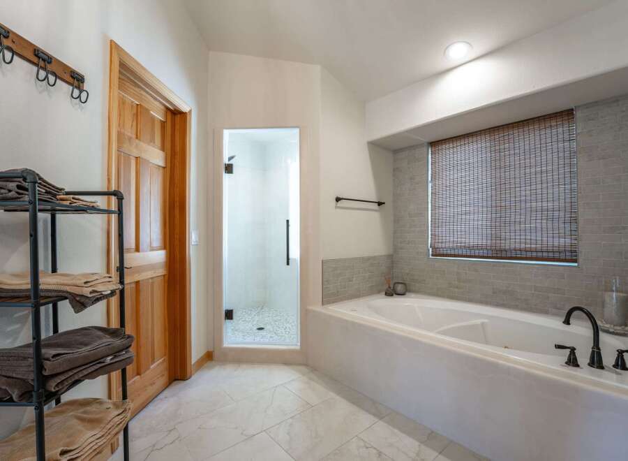 Experience luxury in this stunning bathroom featuring a spacious soaking tub and a separate glass-enclosed shower.