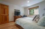 This charming bedroom features a cozy plaid comforter and a wooden dresser topped with a television.