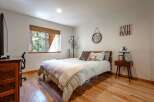 This cozy bedroom features a comfortable queen-size bed with a charming plaid comforter and a plush white throw.