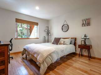 This cozy bedroom features a comfortable queen-size bed with a charming plaid comforter and a plush white throw.