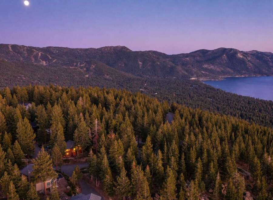 Experience luxury living nestled amidst a serene pine forest with breathtaking views of a majestic lake and mountains.