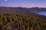 Experience luxury living nestled amidst a serene pine forest with breathtaking views of a majestic lake and mountains.