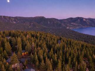 Experience luxury living nestled amidst a serene pine forest with breathtaking views of a majestic lake and mountains.