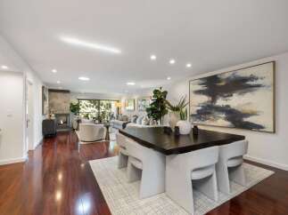 Experience modern living in this spacious open-concept home, featuring a sleek fireplace and a large abstract artwork that anchors the dining area.