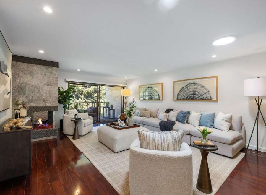 Experience modern living in this stunning living room, featuring a cozy fireplace with a stone accent wall and a spacious sectional sofa perfect for gatherings.