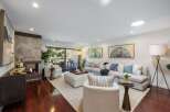 Experience modern living in this stunning living room, featuring a cozy fireplace with a stone accent wall and a spacious sectional sofa perfect for gatherings.