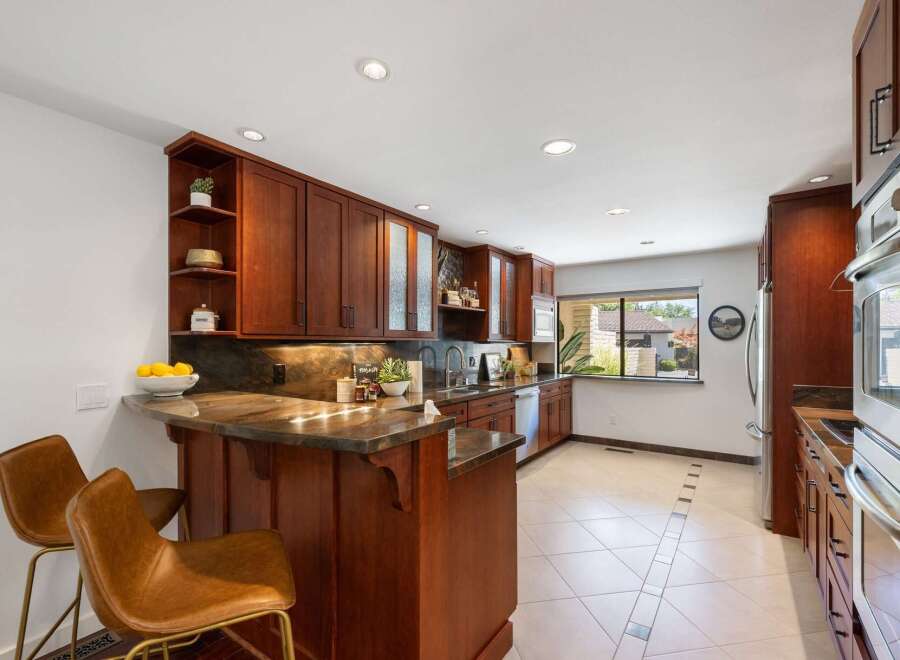 This stunning kitchen boasts rich cherry wood cabinetry and a sleek granite countertop, perfect for culinary enthusiasts.