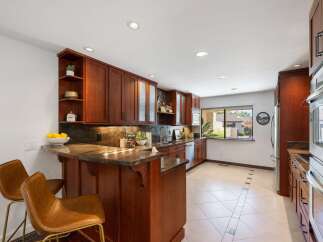 This stunning kitchen boasts rich cherry wood cabinetry and a sleek granite countertop, perfect for culinary enthusiasts.