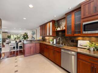 Discover this stunning kitchen featuring rich cherry wood cabinetry and elegant granite countertops.